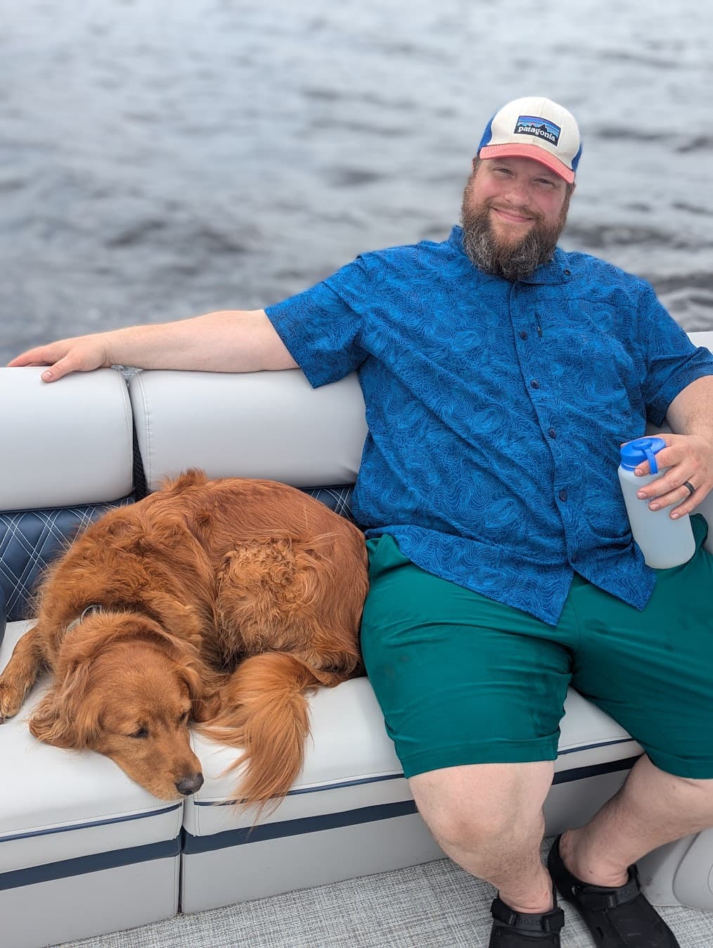 Nate on a boat with Minerva the golden retriever